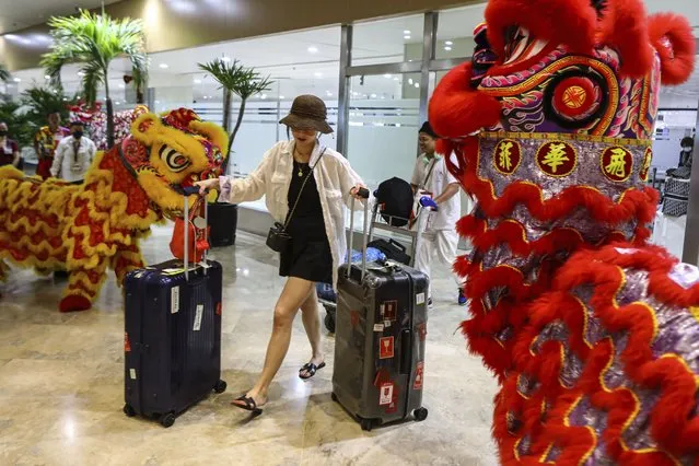 Dragon and Lion performers welcome a Chinese tourist arriving at the Ninoy Aquino International Airport in Manila on Tuesday, Jan. 24, 2023. The expected resumption of group tours from China is likely to bring far more visitors. (Photo by Gerard V. Carreon/AP Photo)