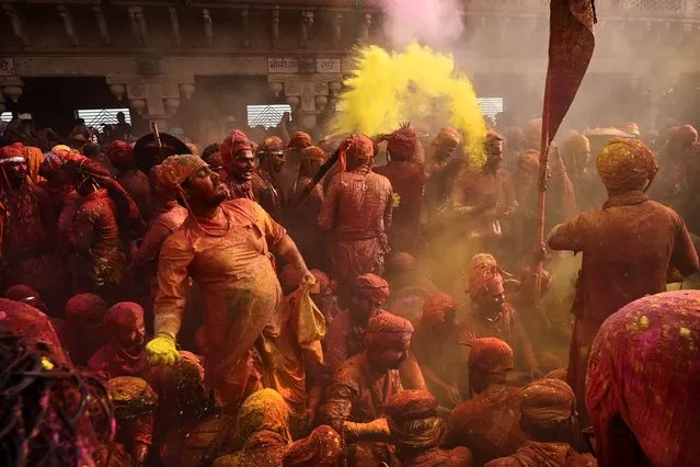 Men from Barsana village smeared with colors play Holi at Nandagram temple in Nandgoan village, 115 kilometers (70 miles) south of New Delhi, India, Wednesday, March 1, 2023. (Photo by Deepanshu Aggarwal/AP Photo)