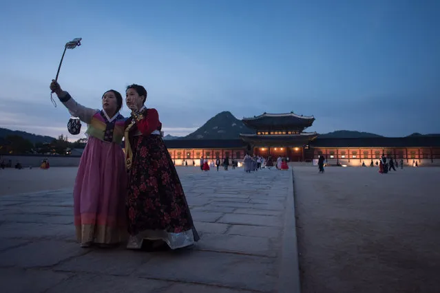 Two women wearing traditional hanbok dresses pose for a selfie before Gyeongbokgung palace in Seoul on October 12, 2016. Samsung Electronics slashed its latest quarterly profit estimate by one third in the wake of a highly damaging recall crisis that ended with the scrapping of its latest flagship smartphone. (Photo by Ed Jones/AFP Photo)