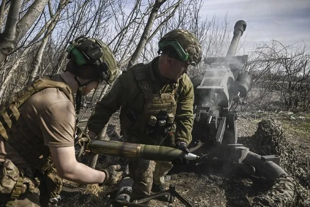 Ukrainian servicemen fire with an M119 105mm howtitzer at Russian positions near Bachmut, on March 23, 2023, amid the Russian invasion of Ukraine. (Photo by Aris Messinis/AFP Photo)