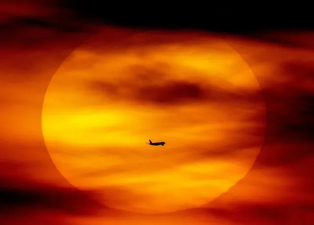 An aircraft passes the rising sun in Frankfurt, Germany, Wednesday, February 22, 2023. (Photo by Michael Probst/AP Photo)