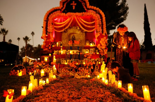 Family members gather at their family altar during Dia de Los Muertos (Day of the Dead) festivities at Hollywood Forever cemetery on November 1, 2025 in Los Angeles, California. Dia de Los Muertos is a traditional Mexican festival with Aztec roots which sees people celebrate and commemorate the spirits of departed ancestors and loved ones. Today was the 26th year for festivities at the cemetery which included more than 50 altars honoring the deceased. (Photo by Mario Tama/Getty Images)
