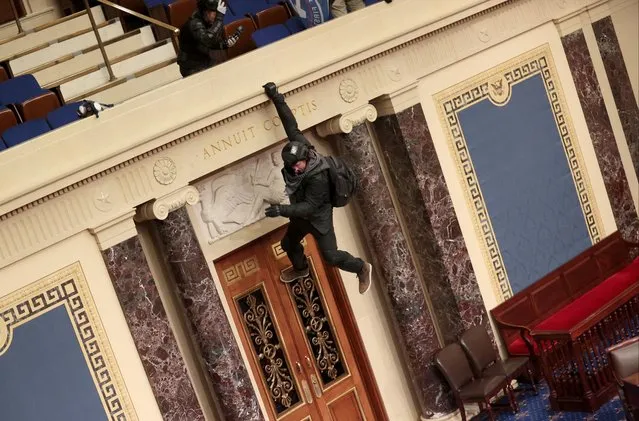 A protester is seen hanging from the balcony in the Senate Chamber on January 06, 2021 in Washington, DC. Congress held a joint session today to ratify President-elect Joe Biden's 306-232 Electoral College win over President Donald Trump. Pro-Trump protesters have entered the U.S. Capitol building after mass demonstrations in the nation's capital. (Photo by Win McNamee/Getty Images)