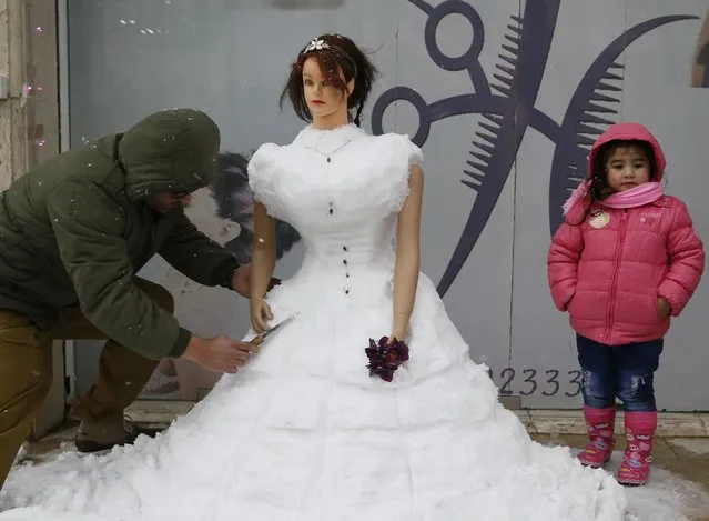 A hairdresser uses a knife to carve a snow sculpture in front of his shop in Basour village, east of Beirut January 9,2015. A storm buffeted the Middle East with blizzards, rain and strong winds on Wednesday, keeping people at home across the region and raising concerns for Syrian refugees facing freezing temperatures in flimsy shelters. (Photo by Jamal Saidi/Reuters)