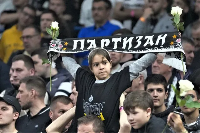 Partizan fans hold up scarves and flowers in memory of the victims of school shooting a day earlier orior the Euroleague basketball match between Partizan and Real Madrid, in Belgrade, Serbia, Thursday, May 4, 2023. A 13-year-old who opened fire Wednesday at his school in Serbia's capital. He killed eight fellow students and a guard before calling the police and being arrested. Six children and a teacher were also hospitalized. (Photo by Darko Vojinovic/AP Photo)
