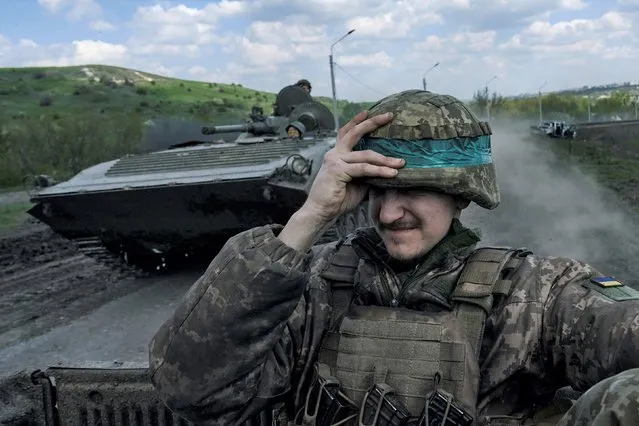 A Ukrainian soldier holds his helmet as he rides an APC in Bakhmut, in the Donetsk region, Ukraine, Wednesday, April 26, 2023. (Photo by Libkos/AP Photo)