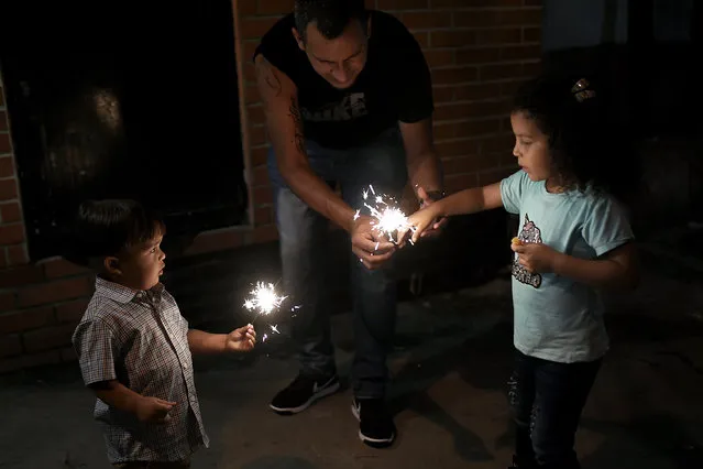 Children play with light sparklers during New Year's Eve at the 23 de Enero neighborhood in Caracas, Venezuela, late Thursday, December 31, 2020, amid the new coronavirus pandemic. (Photo by Matias Delacroix/AP Photo)