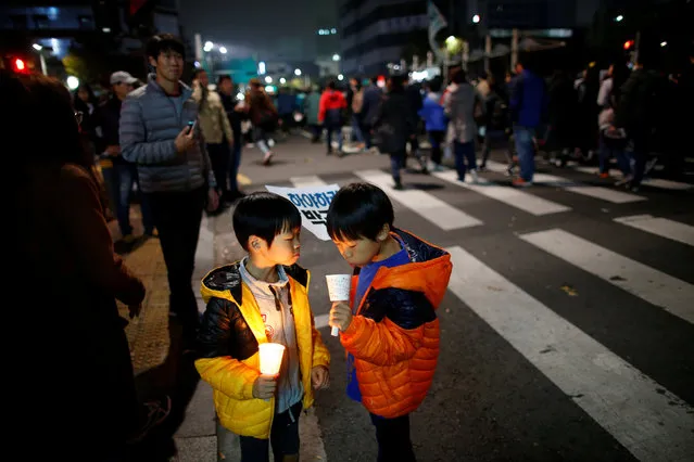 Children watch their candlelight as tens of thousands of South Korean people march during a rally calling on embattled President Park Geun-hye to resign over a growing influence-peddling scandal, in central Seoul, South Korea, November 5, 2016. (Photo by Kim Hong-Ji/Reuters)
