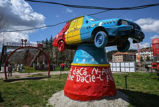 An installation made by visual artist Ion Barbu, representing a communist era DACIA car painted in the colors of the Romanian flag and reading “If we don't have a Dacia, we will make it from a Porsche”, is seen during “The day of open mines” – a cultural event organized by “Petrila Cultural Association” on the site of the closed coal mine in Petrila, Romania, on May 1, 2023. One of the shrinking cities, Petrila, like most of the mining settlements on the Jiului Valley, underwent successive social and economic reconfigurations. The locals, together with the renowned Romanian visual artist Ion Barbu and activists for industrial heritage managed to save some of the mine buildings from demolition. Activations and cultural activities at Petrila reach a wide audience through events that bring visitors from all over the country, while exhibitions, film and mural art lay the groundwork for groups that have the potential to save the mine for the future. (Photo by Daniel Mihailescu/AFP Photo)