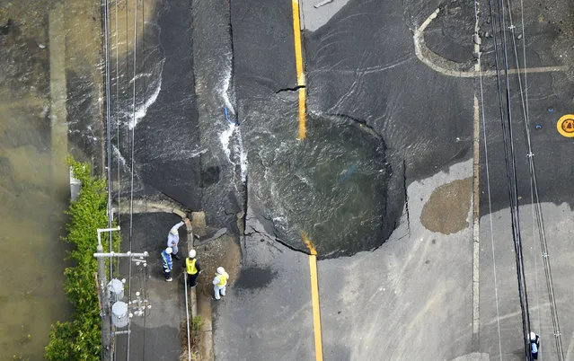 Water flows out from cracks in a road damaged by an earthquake in Takatsuki, Osaka prefecture, western Japan, in this photo taken by Kyodo on June 18, 2018. The massive earthquake registering a weak 6 on the Japanese seismic scale occurred in northern Osaka Prefecture on June 18 th. According to the Meteorological Agency, the depth of the epicenter is estimated to be about 13 kilometers, and the indicative magnitude is estimated to be 6.1. Some aftershocks occurred one after another in the afflicted areas. (Photo by Kyodo News via Reuters)