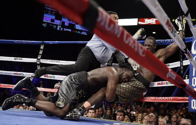 Referee Tony Weeks, left, Deontay Wilder, right, and Bermane Stiverne fall to the mat during the WBC heavyweight championship boxing match Saturday, January 17, 2015, in Las Vegas. (Photo by Isaac Brekken/AP Photo)