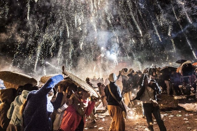 This picture taken on November 12, 2016 shows people protecting themselves from fireworks, being carried by a hot air balloon, that ignited before the balloon was at a sufficient height during the Tazaungdaing Lighting Festival at Taunggyi in Myanmar' s northeastern Shan State. (Photo by Ye Aung Thu/AFP Photo)