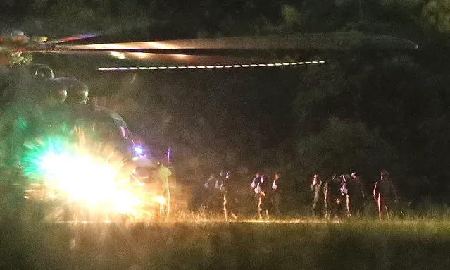 Thai medics and police officers evacuate the first two children with a helicopter after rescued from Tham Luang cave before heading to hospital, at a helicopter pad in Chiang Rai province, Thailand, 08 July 2018. Members of a children soccer team and their assistant coach who have been trapped in Tham Luang cave since 23 June 2018 have been rescued on 08 July 2018. (Photo by Rungroj Yongrit/EPA/EFE)