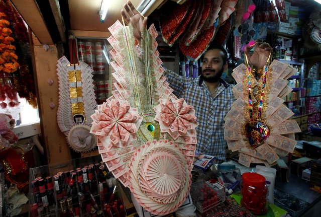 A shopkeeper shows garlands made of Indian currency notes to a customer at a market in Chandigarh, India, November 13, 2016. (Photo by Ajay Verma/Reuters)