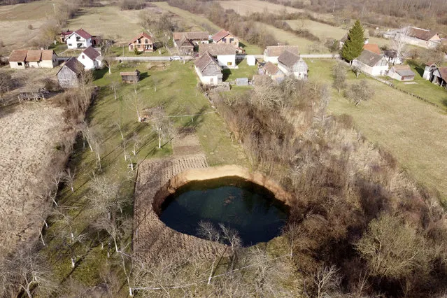 This aerial photo shows a sinkhole in the village of Mececani, central Croatia, Thursday, March 4, 2021. A central Croatian region about 40 kilometers (25 miles) southwest of the capital Zagreb is pocked with round holes of all sizes, which appeared after December's 6.4-magnitude quake that killed seven people and caused widespread destruction. Scientists have been flocking to Mecencani and other villages in the sparsely-inhabited region for observation and study. (Photo by Darko Bandic/AP Photo)