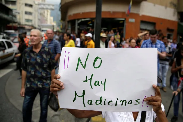 An opposition supporter holds a placard that reads “There are no medicines”, during a protest against shortage of medicines and to demand a referendum to remove President Nicolas Maduro in Caracas, Venezuela November 17, 2016. (Photo by Marco Bello/Reuters)
