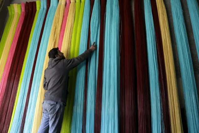 A man adjusts plastic strings, used to produce mats, inside a mat factory in the rebel-controlled area of Maarshureen town in Idlib province, Syria, December 22, 2015. (Photo by Khalil Ashawi/Reuters)