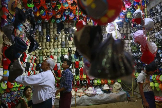 A man buys a cap at a shop at the Kyaik-Khauk pagoda festival in Tanlyin township, outside Yangon, February 2, 2015. (Photo by Soe Zeya Tun/Reuters)