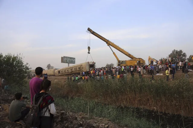 A crane is used to lift a part of a passenger train that derailed injuring some 100 people, near Banha, Qalyubia province, Egypt, Sunday, April 18, 2021. (Photo by Fadel Dawood/AP Photo)