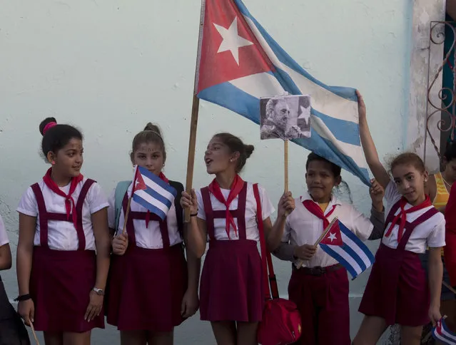Girls wait for the arrival of the caravan carrying the ashes of Cuba's leader Fidel Castro during a funeral procession that retraces the path of his triumphant march into Havana nearly six decades ago, in Esperanza, Cuba, Wednesday, November 30, 2016. Castro's ashes have begun a four-day journey across Cuba from Havana to their final resting place in the eastern city of Santiago.  (Photo by Ricardo Mazalan/AP Photo)