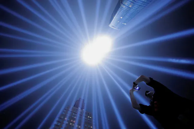 EMT with the Fire Department of New York and first responder Jason Butscher takes a photo while standing within the Tribute In Light installation as it is illuminated over lower Manhattan marking the 17th anniversary of the 9/11 attacks in New York City, U.S., September 11, 2018. (Photo by Andrew Kelly/Reuters)