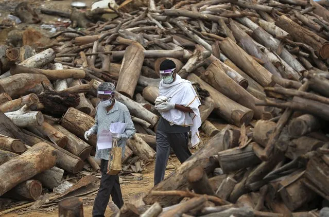 A family member carries an urn containing ashes from the remains of a COVID-19 victim at an open crematorium on the outskirts of Bengaluru, Karnataka state, India, Wednesday, May 12, 2021. (Photo by Aijaz Rahi/AP Photo)