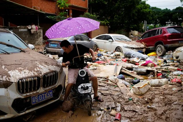 A man rides a scooter through mud and debris after heavy rainfall flooded Tangxia town in Dongguan, Guangdong province, China on September 9, 2023. (Photo by Aly Song/Reuters)