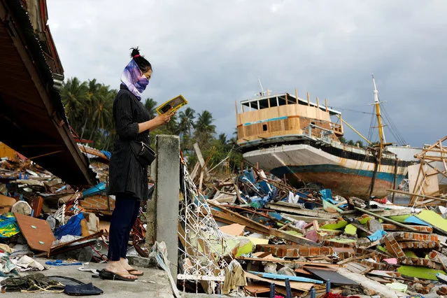 A woman reads a Quran that she found in a house in the area hit by the tsunami on the coastline in Palu, Central Sulawesi, Indonesia October 13, 2018. (Photo by Jorge Silva/Reuters)