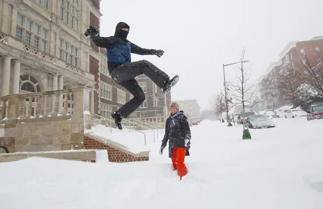 Ian Wright, left, leaps into a snow bank as his wife Rebecca, center, watches on their street in the Columbia Heights neighborhood of in Washington, Saturday, January 23, 2016. Millions of people awoke Saturday to heavy snow outside their doorsteps, strong winds that threatened to increase through the weekend, and largely empty roads as residents from the South to the Northeast heeded warnings to hunker down inside while a mammoth storm barreled across a large swath of the country. (Photo by Pablo Martinez Monsivais/AP Photo)