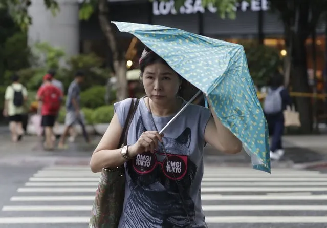 A woman struggles with her umbrella against gusts of wind generated by Typhoon Haikui in Taipei, Taiwan, Sunday, September 3, 2023. (Photo by Chiang Ying-ying/AP Photo)