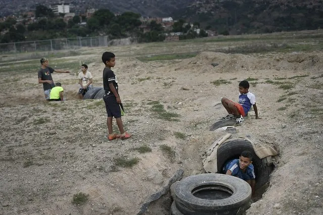 Children play in an abandoned military exercise field in the Ojo de Agua neighborhood of Caracas, Venezuela, Sunday, May 23, 2021. (Photo by Matias Delacroix/AP Photo)