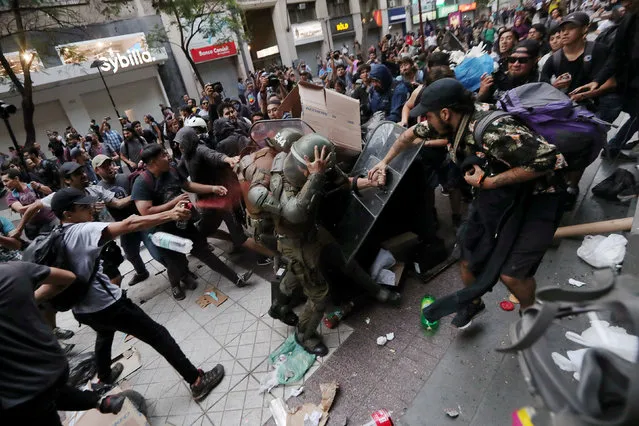 Mapuche indigenous activists clash with riot policemen during a protest demanding justice for Camilo Catrillanca, an indigenous Mapuche man who was shot in the head during a police operation as well as for their indigenous rights and lands for their communities, in Santiago, Chile December 27, 2018. (Photo by Ivan Alvarado/Reuters)