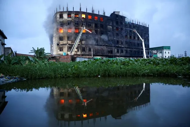 Flames rise the morning after a fire broke out at a factory named Hashem Foods Ltd. in Rupganj of Narayanganj district, on the outskirts of Dhaka, Bangladesh, July 9, 2021. (Photo by Mohammad Ponir Hossain/Reuters)