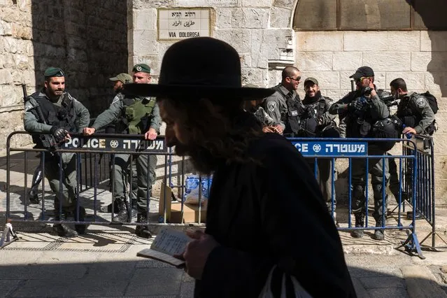 An ultra-Orthodox Jew reading from his prayer book as he walks past a group of Israeli riot police on guard duty on the Via Dolorosa at the 3rd Station of the Cross in Jerusalem's Old City, 12 February 2016. Israel continues with a strong security presence in the Old City but did not restrict attendance at Friday prayers at al-Aqsa Mosque. (Photo by Jim Hollander/EPA)