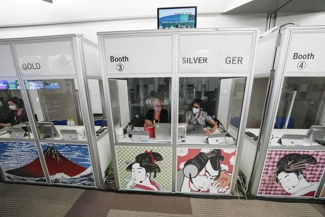 Interpreters work at the main press center during the 2020 Summer Olympics, Friday, July 30, 2021, in Tokyo, Japan. Unlike previous Olympics, all the interpretation is being done remotely with most interpreters working in booths at the main center. Their simultaneous translation can be accessed at all Olympic venues on an app. This eliminates interpreters getting tied up in traffic heading to an venue. (Photo by Luca Bruno/AP Photo)