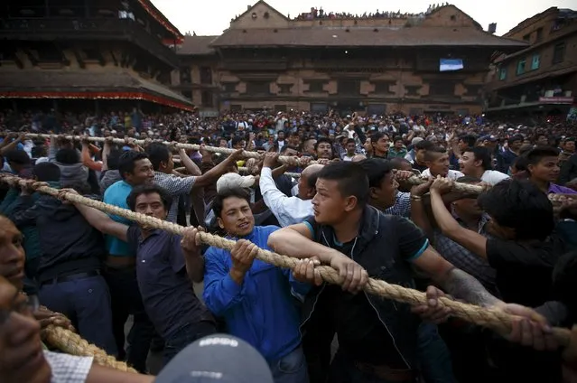 Devotees hold on to the ropes tied to the chariot of God Bhairab as they pull it through the city centre of Bhaktapur near Kathmandu during the Bisket festival April 10, 2015. (Photo by Navesh Chitrakar/Reuters)