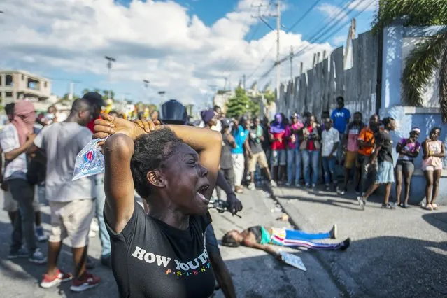 A woman cries near the body of another woman shot dead by the police during a protest demanding the resignation of Prime Minister Ariel Henry in the Delmas area of Port-au-Prince, Haiti, Monday, October 10, 2022. (Photo by Odelyn Joseph/AP Photo)