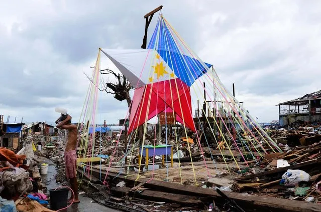 A man takes a bath beside a giant Christmas star fashioned into a Philippine flag on Christmas Eve in Tacloban, on December 24, 2013. (Photo by Dondi Tawatao/Getty Images)