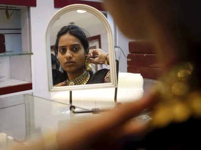 A woman tries on a gold necklace inside a jewelry showroom at a market in Mumbai April 8, 2015. Gold demand in the world's biggest consumer India risks falling for a second straight year in 2015, as millions of Indian farmers hit by erratic weather and falling commodity prices trim gold purchases. (Photo by Shailesh Andrade/Reuters)