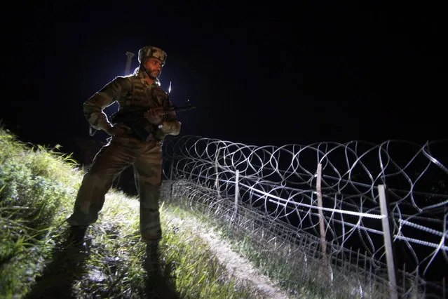 In this December 22, 2013 photo, an Indian army soldier stands guard along barbed wire near the Line of Control (LOC), that divides Kashmir between India and Pakistan, at Krishna Ghati (KG Sector) in Poonch, 290 kilometers (180 miles) from Jammu, India. (Photo by Channi Anand/AP Photo)