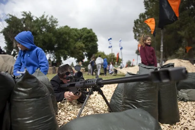 An Israeli youth looks through the sight of a weapon during a display of Israeli Defense Forces (IDF) equipment and abilities at the West Bank settlement of Kiryat Arba, April 23, 2015, during celebrations for Israel's Independence Day, marking the 67th anniversary of the creation of the state. (Photo by Ronen Zvulun/Reuters)