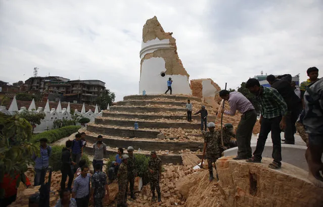 Volunteers work to remove debris at the historic Dharahara tower, a city landmark, after an earthquake in Kathmandu, Nepal, Saturday, April 25, 2015. (Photo by Niranjan Shrestha/AP Photo)