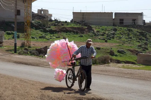 A man sells cotton candy as he pushes his bicycle along a street in the rebel held al-Ghariyah al-Gharbiyah town, in Deraa province, Syria February 28, 2016. Picture taken February 28, 2016. (Photo by Alaa Al-Faqir/Reuters)