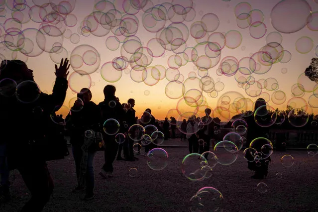 Tourists play with soap bubbles during sunset at “Terrazza del Pincio” on February 6, 2019 in Rome, Italy. (Photo by Antonio Masiello/Getty Images)