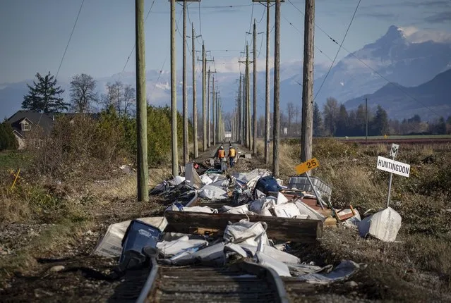 Southern Railway of British Columbia (SRY Rail Link) employees survey a section of rail lines that are washed out in numerous places and covered in debris after flood waters receded following heavy rains in Abbotsford, British Columbia, Friday, November 19, 2021. (Photo by Darryl Dyck/The Canadian Press via AP Photo)