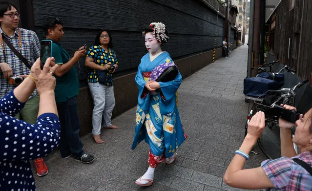 Tourists take photographs of a maiko, or apprentice geisha, walking through the Gion area of Kyoto, Japan, on Thursday, May 28, 2015. (Photo by Akio Kon/Bloomberg)