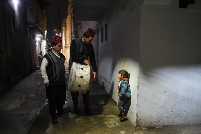 Ramadan drummer Gufran Samer talks with a child as he walks down the streets while banging his drum to wake people up for sahoor (pre-dawn) meal, in Mosul, Iraq on March 23, 2024. Gufran Samer, who has been a mesaharati for 6 years, carries on tradition throughout Ramadan. (Photo by Ismael Adnan Yaqoob/Anadolu via Getty Images)