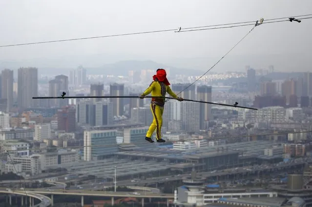 Aisikaier Wubulikasimu, a 42-year-old Uighur acrobat, walks backwards on tightrope with his eyes covered by a red cloth, during a challenge in Kunming, Yunnan province, China, May 16, 2015. Aisikaier successfully completed the challenge on a 100-metre-long tightrope between two buildings about 150 metres above ground, local media reported. (Photo by Wong Campion/Reuters)