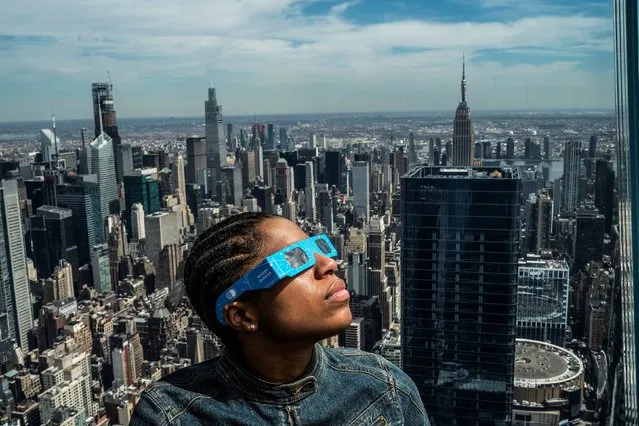 A person watches the start of the eclipse as people gather on the observation deck of Edge at Hudson Yards in New York City on April 8, 2024. (Photo by Eduardo Munoz/Reuters)