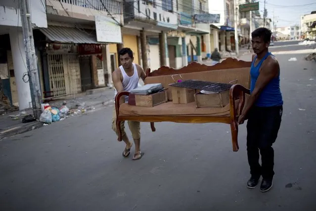 Two men carry a settee and personal belongings recovered from their earthquake-damaged home, in Manta, Ecuador, Wednesday, April 20, 2016. (Photo by Rodrigo Abd/AP Photo)